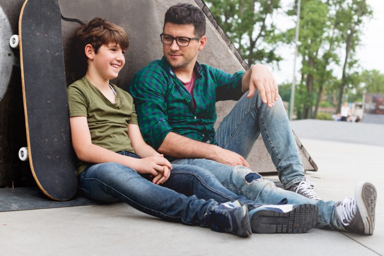 Young boy sitting with a mentor in the park