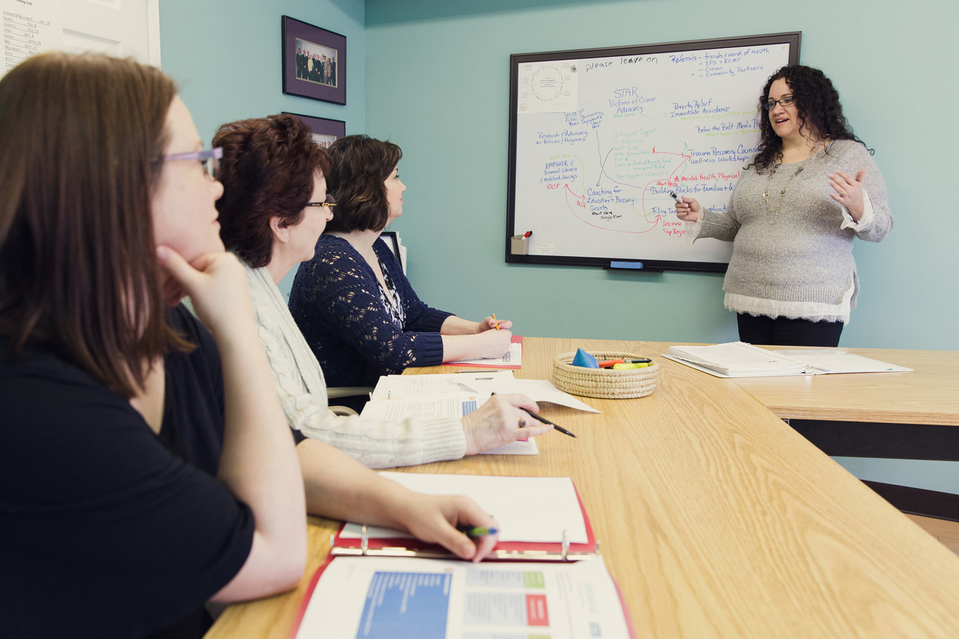 A woman delivers an Empower U financial literacy workshop to three other seated women.