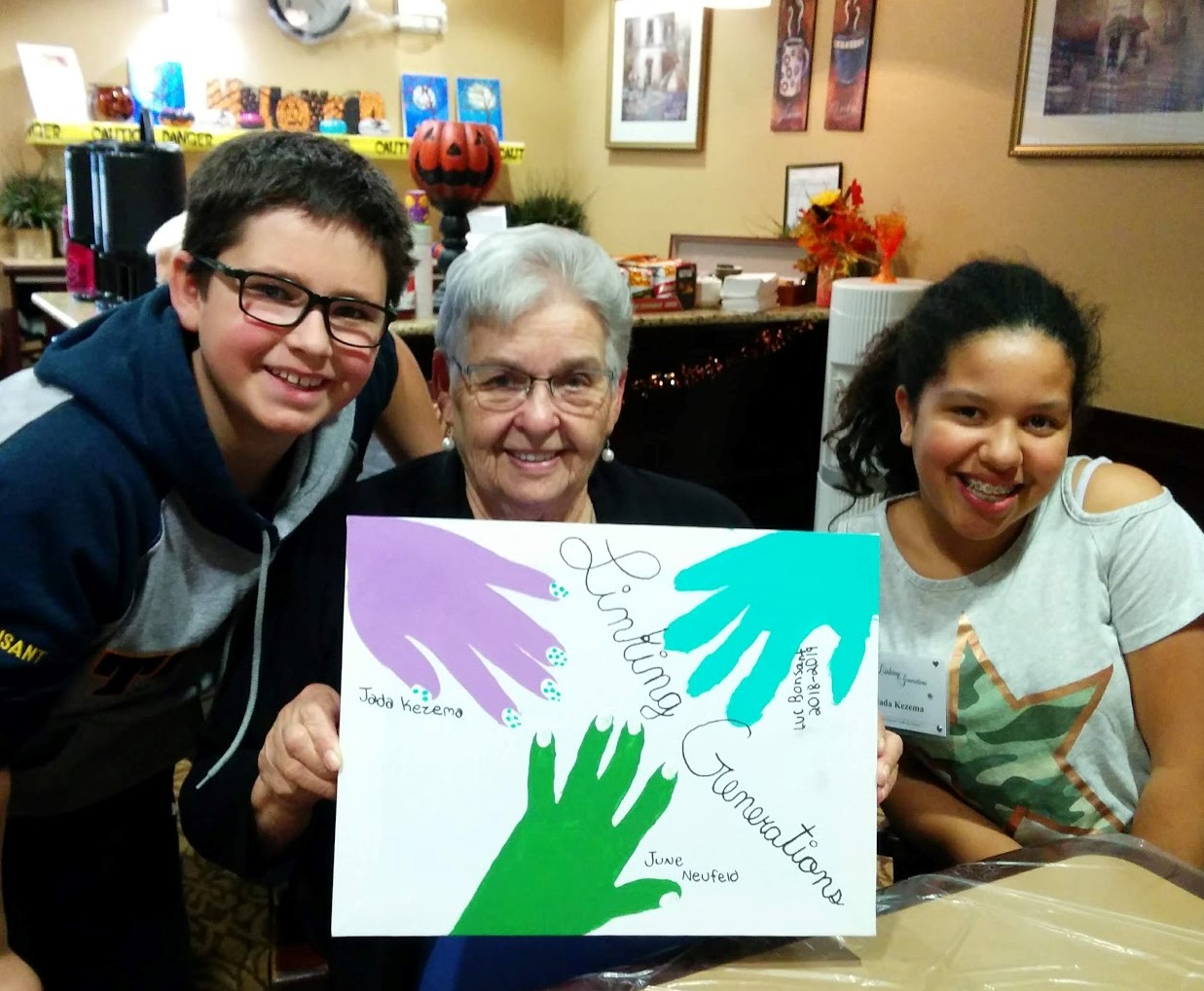 two children and a senior hold up a linking generations sign