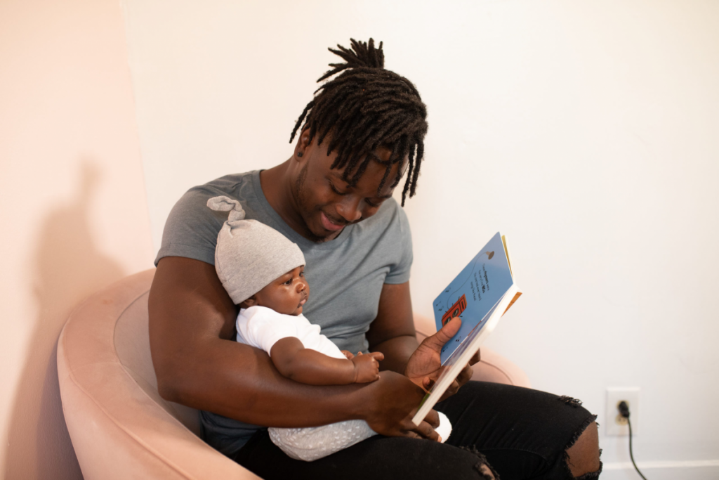 a dad smiles reading to a baby