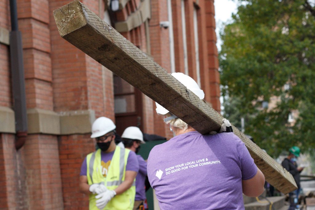 Woman carrying lumber with hard hat