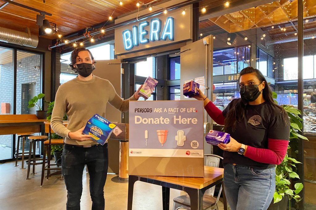 Two volunteers setting up display for Period Promise campaign