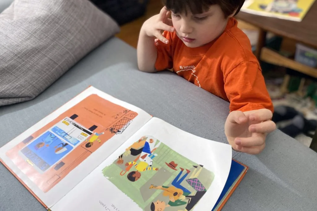 A young boy reads through a picture book