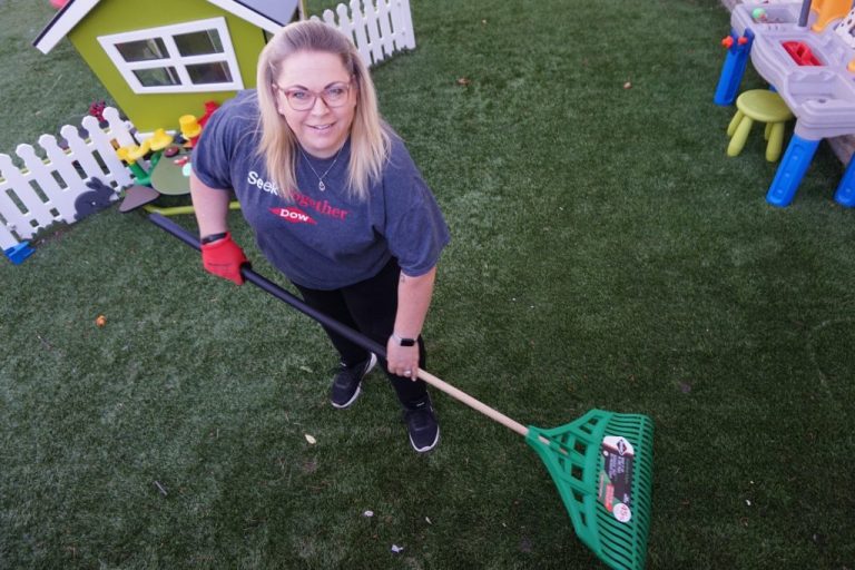 Volunteer smiles while doing lawn maintenance.