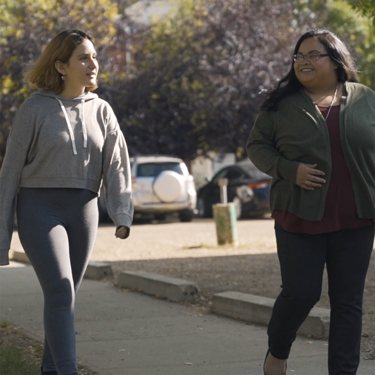 Two young women walk together and smile