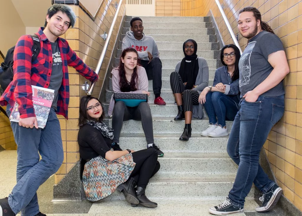 Students stand and sit together in a school stairwell