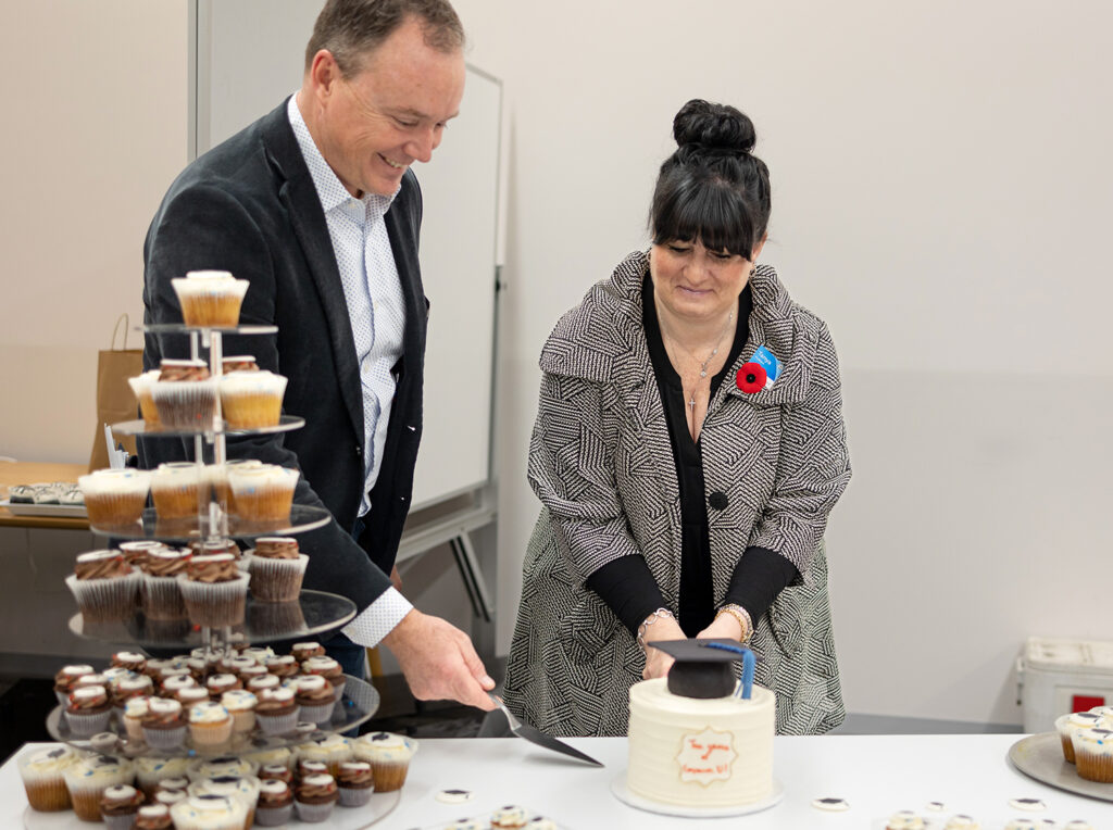 People smiling as a cake is being cut