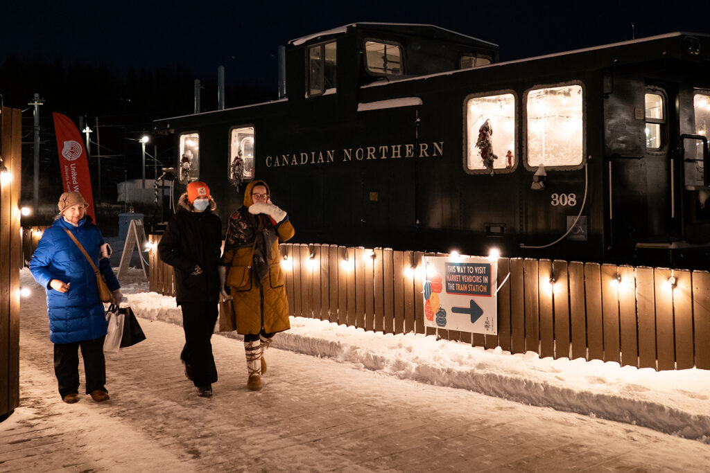 Family explores Christmas market. Fort Edmonton Park train in the background