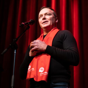 Rob Yager wearing United Way red scarf speaking at media event