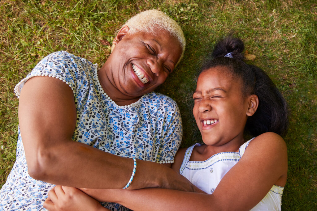 Black girl and grandmother lying on grass, overhead close up