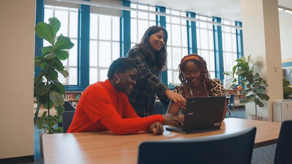 Students get homework help and mentorship support from school staff in a library.