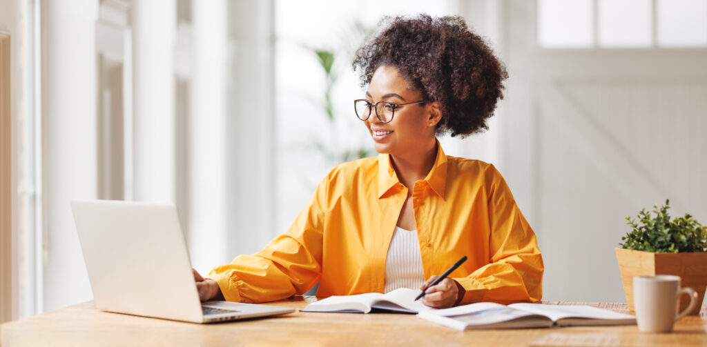 beautiful smiling african american woman works remotely on laptop from home