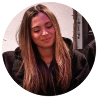 Young woman with long brown hair, looking down, smiling gently.